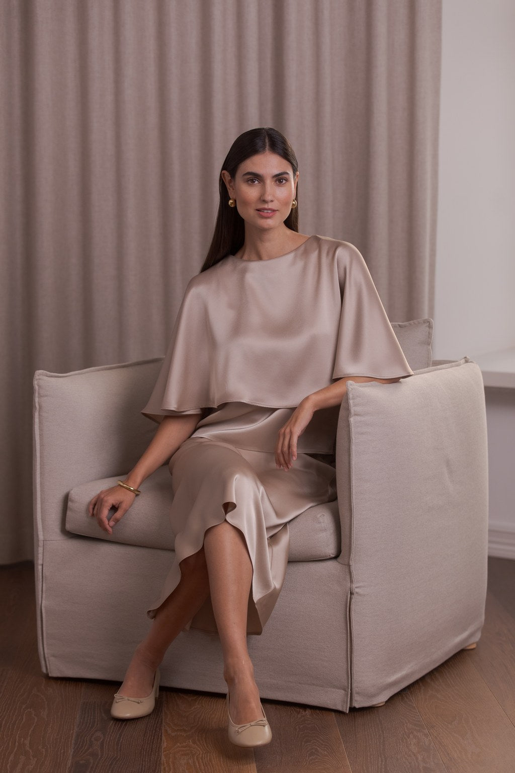 Nainen, jonka päällä Original Storyn satiinikeeppi ja midi-satiinihame sävyssä latte