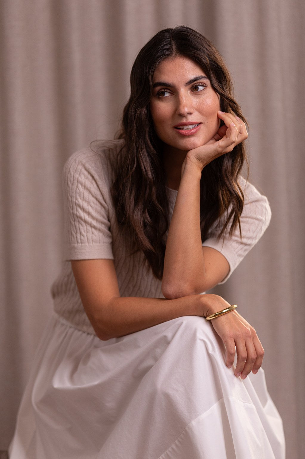 Nainen, jonka päällä Original Storyn palmikkoneule, joka valmistettu kashmirista. Sävyssä latte.