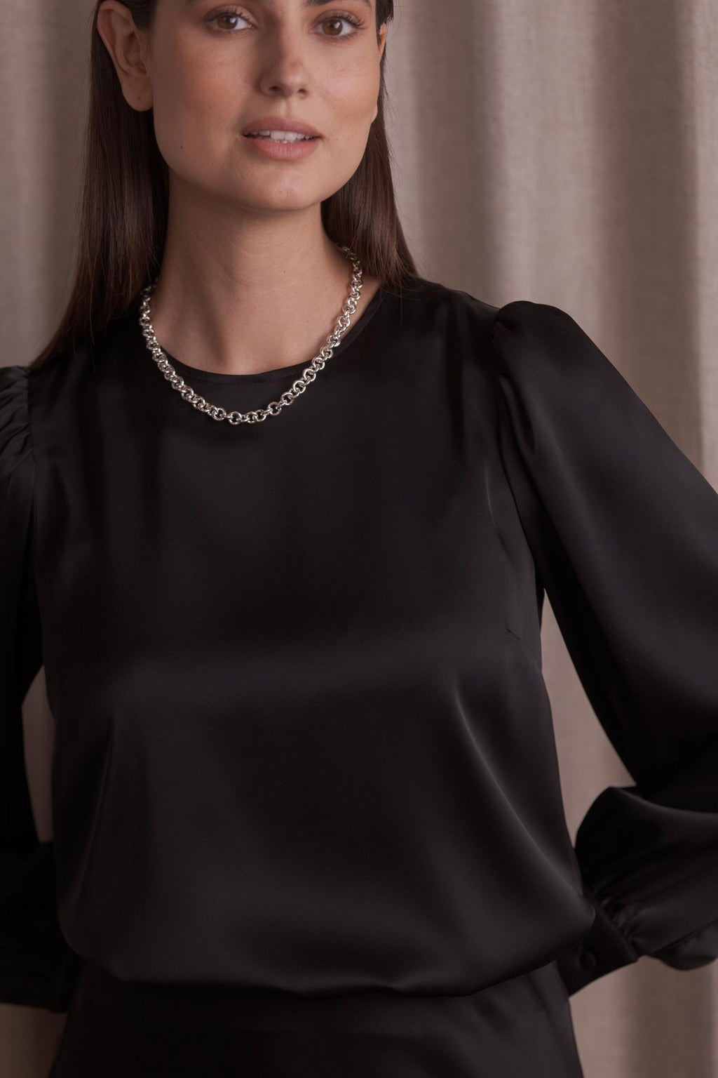 Lähikuva Original Storyn mustasta pitkähihaisesta satiinipaidasta puhvihihoilla.