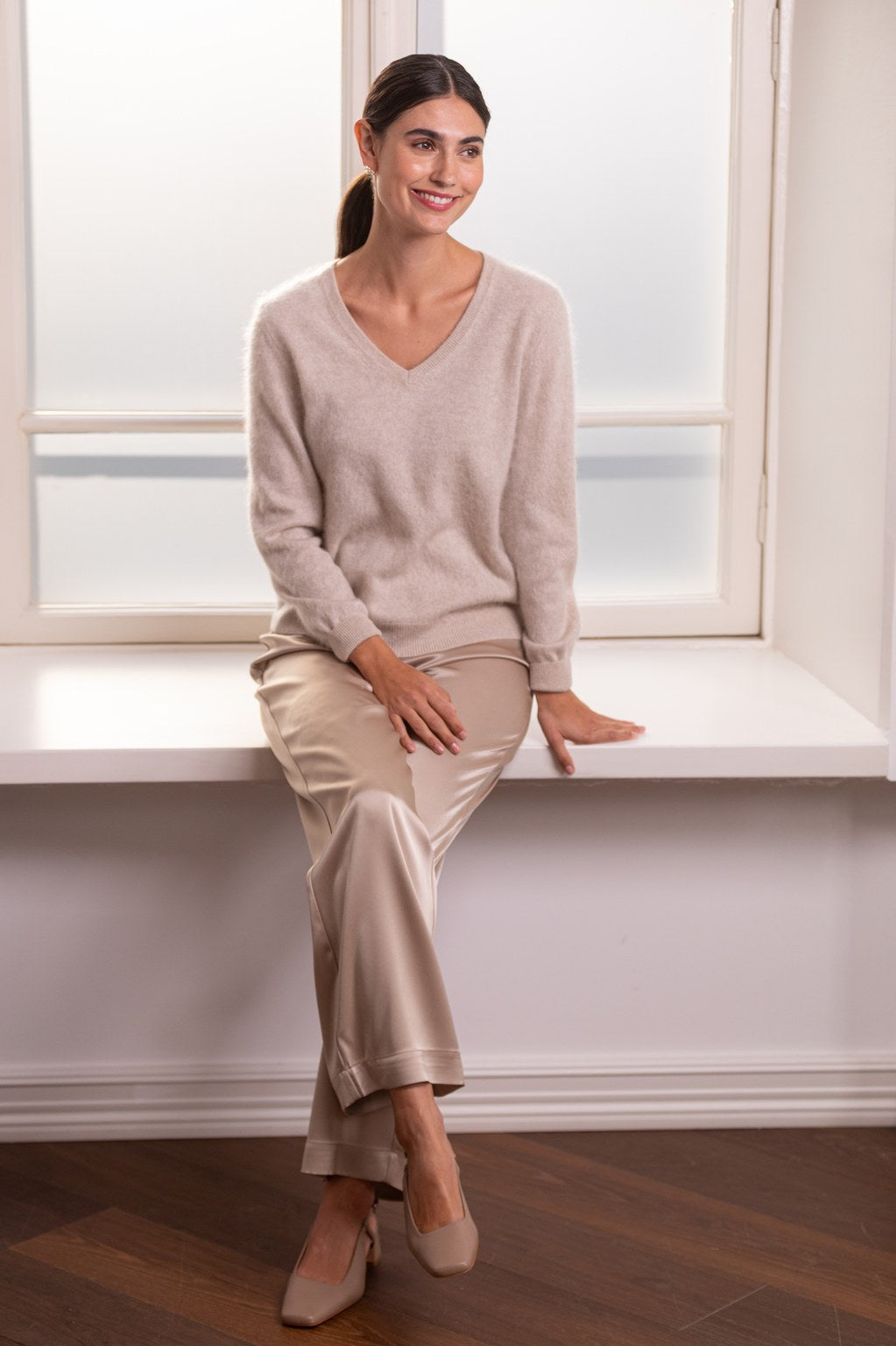 Nainen, jonka päällä on Original Storyn pitkähihainen kashmirneule v-kaula-aukolla, latte