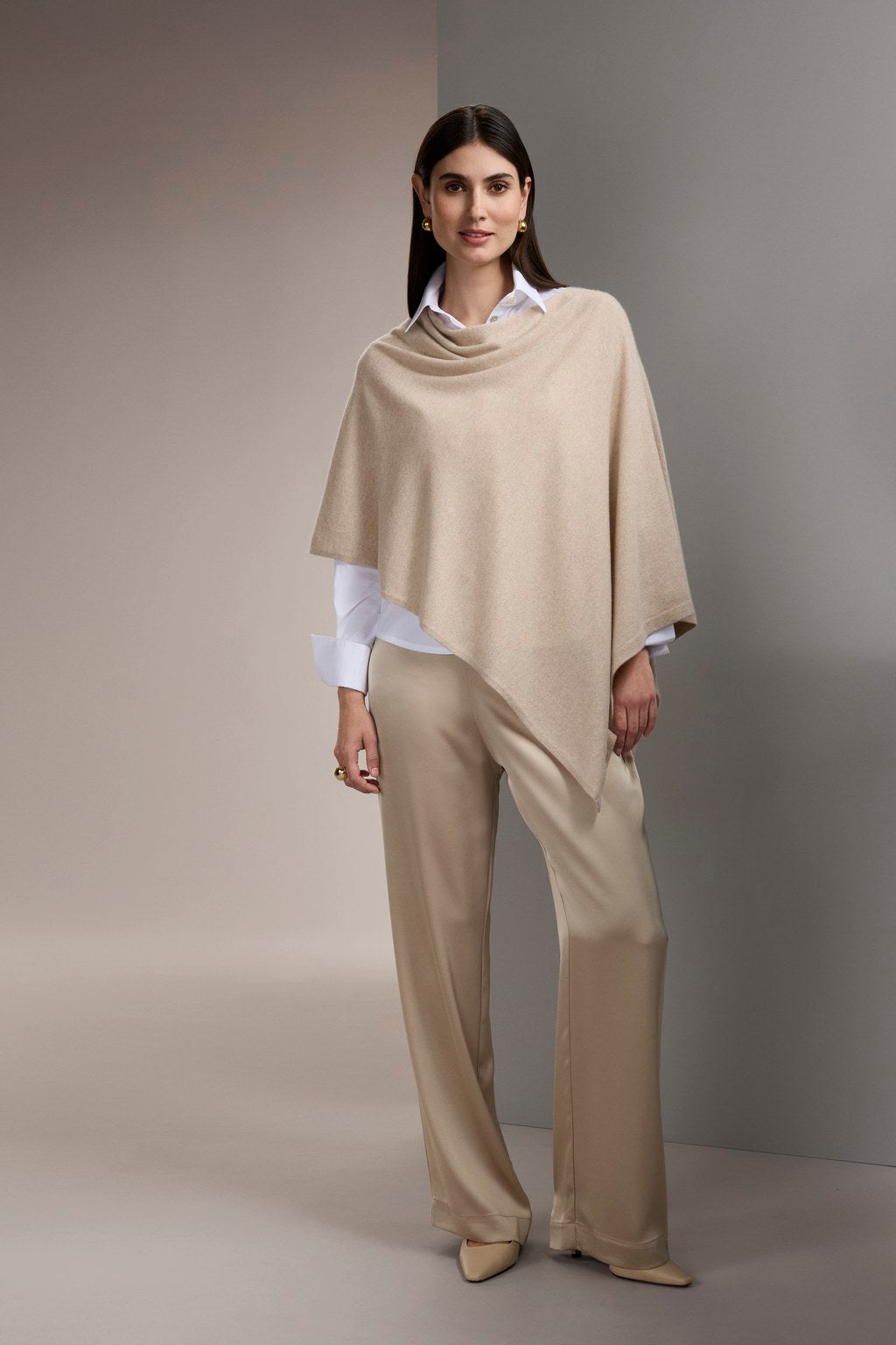 Nainen, jonka päällä on Original Storyn kashmirista valmistettu poncho, latte.