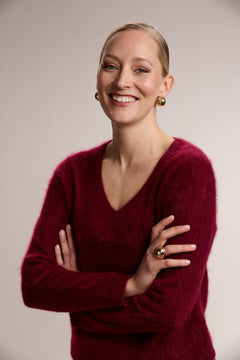 A woman is wearing a long sleeve brushed cashmere v-neck sweater, burgundy.