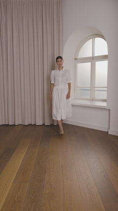 Nainen, jonka päällä Original Storyn puuvillakauluspaita puhvihihalla sekä valkoinen leveähelmainen hame.